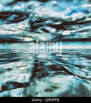 A cold, tranquil ocean beneath dark storm clouds, creating dramatic reflections on the water surface Stock Photo