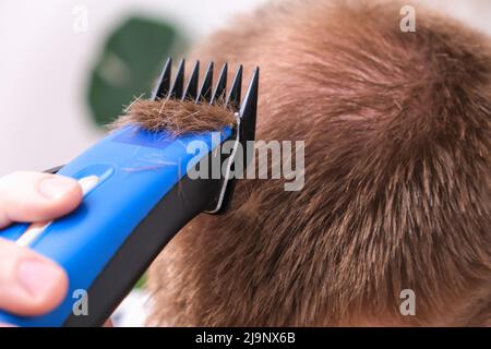 A man cuts his hair with a clipper. Cutting a short hairstyle at home. Close-up. Stock Photo