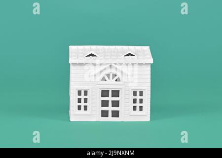 Simple white house model on teal background Stock Photo