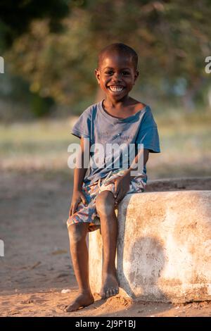 Mali,Kenya - Agust 13 2021:Happy boy without shoes waiting by the roadside in Africa. Stock Photo