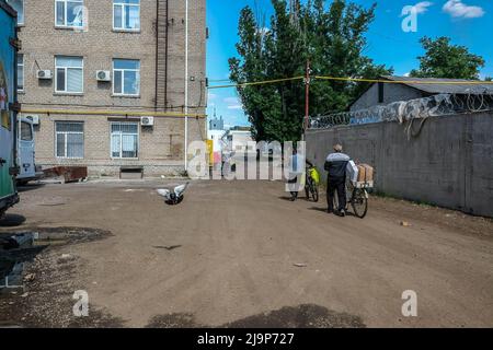 Civilians seen leaving the center of distribution of humanitarian aid of the city with boxes of humanitarian aid. Severodonetsk, the largest city under Ukrainian control in Luhansk province, has come under intense artillery and missile fire from Russian army. The city is almost isolated by the rest of the region, there is one main road connecting the city to Kramatorsk, Russian army is trying to occupy and control it to cut provisions and supplies to the city. Military experts suggest the possibility that Severodonetsk may fall under siege according to the Mariupol scenario. Stock Photo