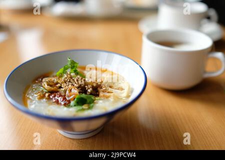 A bowl of Japanese rice porridge with traditional condiments at hotel breakfast buffet Stock Photo