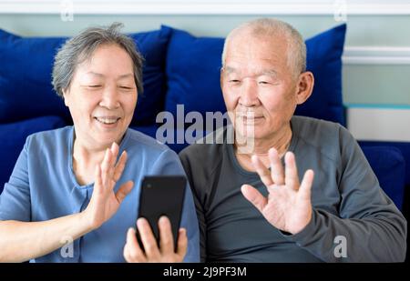 Senior couple doing video call via app on mobile phone at home Stock Photo