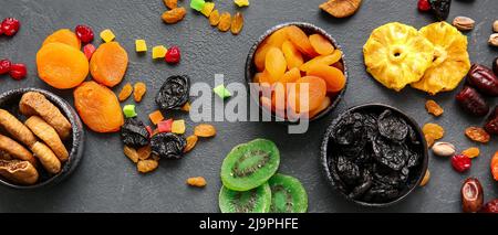 Bowls with different dried fruits on dark background, top view Stock Photo
