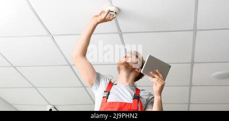 Technician installing smart home security system in room Stock Photo