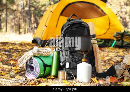 Tourist's survival kit and camping tent in autumn forest Stock Photo