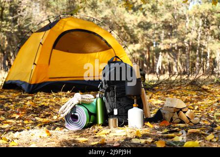 Tourist's survival kit and camping tent in autumn forest Stock Photo