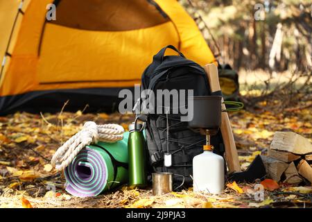 Tourist's survival kit and camping tent in autumn forest Stock Photo