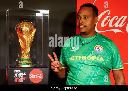 Addis Ababa, Ethiopia. 24th May, 2022. A man poses with the displayed trophy during the FIFA World Cup Trophy Tour event in Addis Ababa, Ethiopia, on May 24, 2022. Credit: Michael Tewelde/Xinhua/Alamy Live News Stock Photo