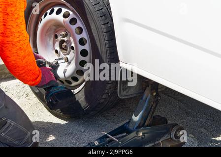 Mechanic changing car tire with tool. road help, changing and repairing tire, wheel. Stock Photo