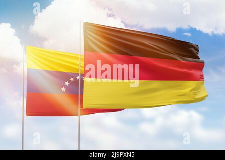 Sunny blue sky and flags of germany and venezuela Stock Photo