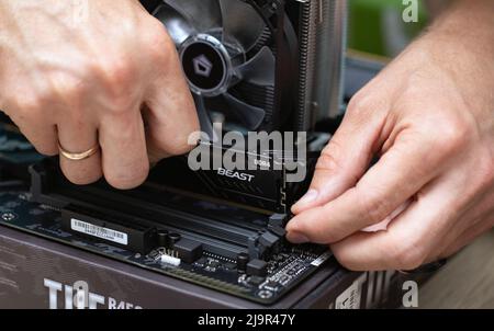Close up of technician man installing Fury Beast RAM DDR4 stick on motherboard of professional computer for cryptocurrency mining. Russia, 17.08.2021 Stock Photo