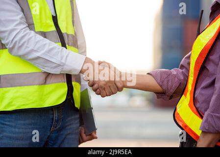 Businessman and engineers working successful handshake together into container for loading. Industrial and logistic concept Stock Photo