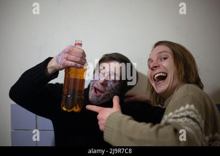 Guys drink alcohol at a party. Crazy guys having fun with beer. The guy with the paint on his face enjoys life. Emotions of people addicted. Creative Stock Photo