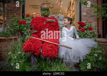 London, UK. 25th May 2022. Chelsea in Bloom: Young dancers from Grace & Poise Academy, the first Muslim Ballet School, pose with the numerous British icon themed floral installations in Chelsea. Dancer seen here with a Chelsea Pensioner floral design on Pavilion Road. Credit: Guy Corbishley/Alamy Live News Stock Photo