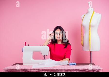 sewing pattern,sewing machine and maniken in studio pink background.seamstress curve template. tailor creates a collection outfits sews clothes in Stock Photo