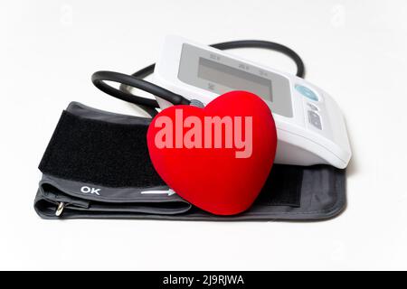 Large red heart shape on a blood pressure measuring device. Healthcare at home. Stock Photo