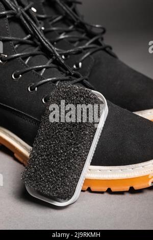 Black hard sponge next to suede black winter boots. Stock Photo