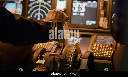 Aircraft captain in cockpit command taking off with airplane, throttling power engine lever to navigate radar compass. Airline service to fly plane with dashboard and control panel. Close up. Stock Photo