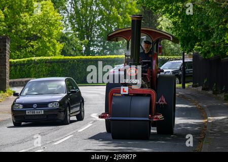 Vintage restored heavy old-fashioned red steam-powered vehicle (black chimney, L-plate) overtaken - Burley-in-Wharfedale, West Yorkshire, England, UK. Stock Photo