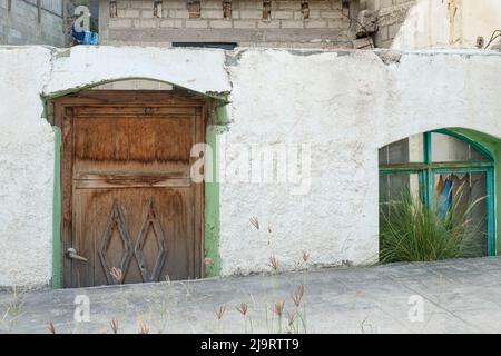 Todos Santos, Mexico. Wooden gate and broken window in a stucco wall. Stock Photo