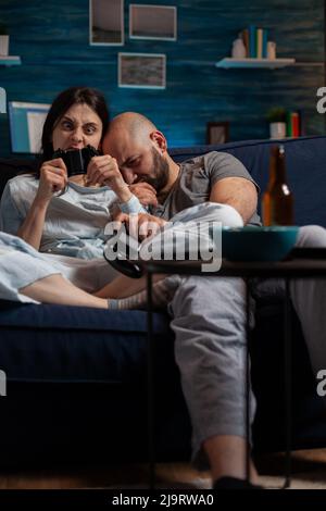 Boyfriend and girlfriend feeling angry about lost videogames, playing online on cyberspace. Frustrated couple losing gameplay on television console, gaming in play competition. Stock Photo