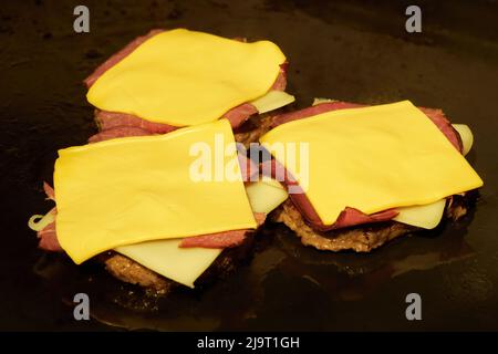 Burgers, hamburgers or cheeseburgers with smoked meat cooking on the grill. Stock Photo
