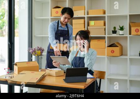 Asian couples doing SMEs deliver their products online to customers who order products via the Internet, helping to sell happily : Work From Home Stock Photo