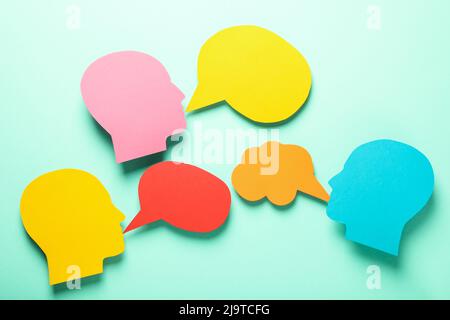Paper heads with speech bubbles on mint background Stock Photo