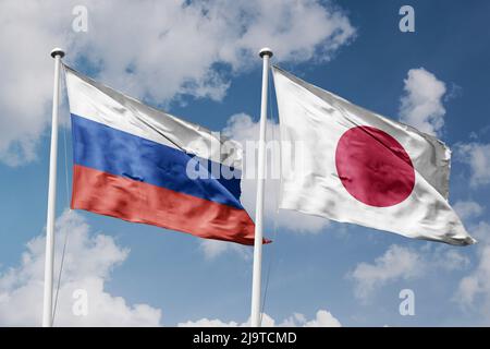 Russia and Japan two flags on flagpoles and blue cloudy sky background Stock Photo