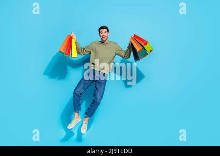 Full size photo of funky young brunet guy jump wear shirt jeans shoes isolated on blue background Stock Photo