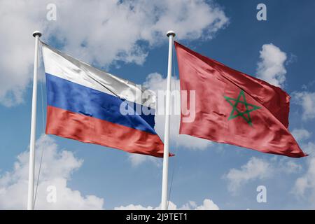 Russia and Morocco two flags on flagpoles and blue cloudy sky background Stock Photo