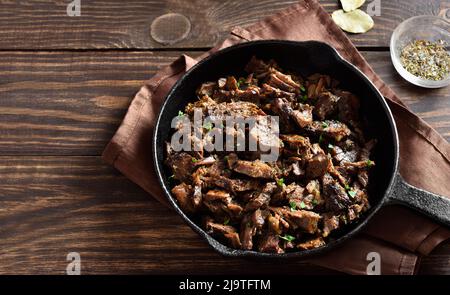 Slow cooked pulled beef in cooking pan on wooden background. Stock Photo