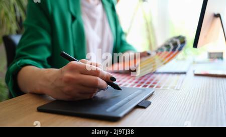 Designer draws sketches on graphics tablet and holds color palette Stock Photo