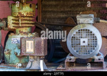 Old rusty abandoned backhoe, heavy equipment, amongst trees with rusty parts. Stock Photo