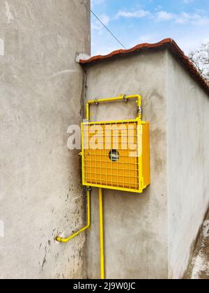 Gas meter mounted on the house wall in yellow protective casing Stock Photo