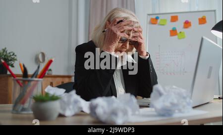 Tired senior business woman use laptop, having nervous breakdown at work, migaine, headache problems Stock Photo