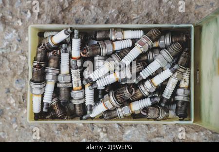 Box with old used car spark plugs close-up. Automotive background Stock Photo
