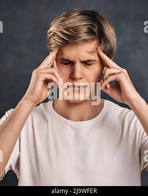 young handsome guy thinking on gray background. Stock Photo