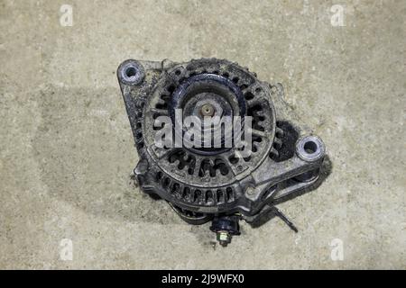 Old dirty car generator on a gray background close-up. Car parts Stock Photo
