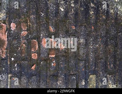 Aged and weathered concrete and black mold and mildew covered brick wall with pieces of broken red pottery clay scattered Stock Photo