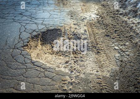 Large pit on the old country road in winter close-up. Mud and snow. Outdoors Stock Photo