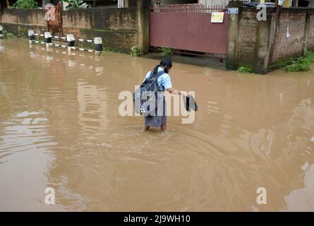 Commuters wades across a flooded street after heavy rains, in Guwahati ...