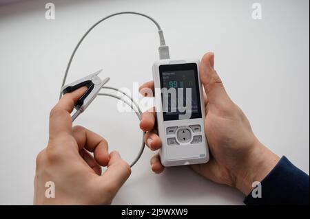 Man using finger pulse oximeter, healthcare monitoring concept. Pulse oximeter on a background Stock Photo