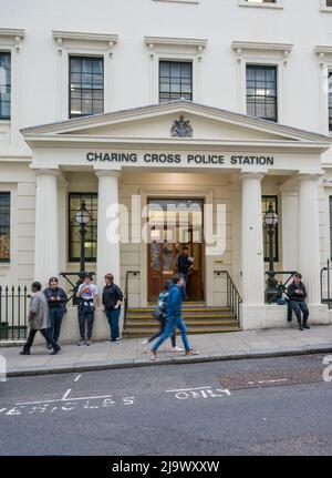 People passing by and others standing outside the main entrance to Charing Cross police station, Agar Street, London, England, UK. Stock Photo