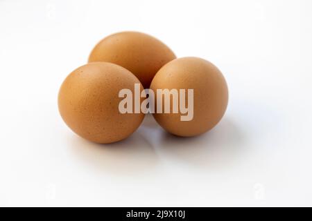Chicken eggs on a white background, close up, three raw eggs. Stock Photo