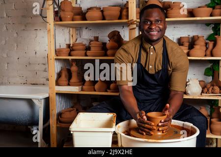 happy dark-skinned african american businessman potter man molding In workshop. sculptor pottering clay pot in a studio workplace. creativity and Stock Photo