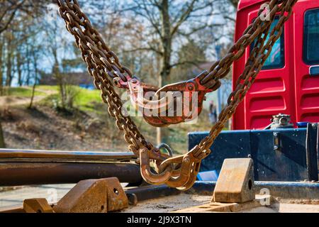 Berlin, Germany - March 5, 2022: Massive and rusty chains and hooks on the load area of a truck. Stock Photo