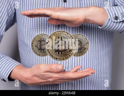 Bitcoin coins levitating between man hands. Cryptocurrency, digital money. Financial concept in abstract style. High quality photo Stock Photo