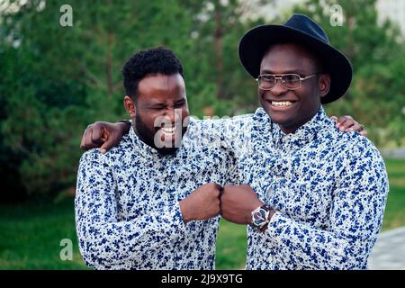 two black men in stylish suits meeting in a summer park. African-Americans friends hispanic businessman embrace high five greeting each other teamwork Stock Photo